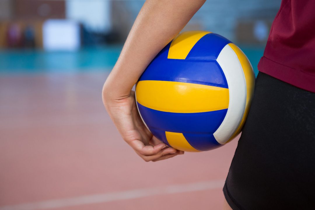 Close-up of female player holding volleyball in the court